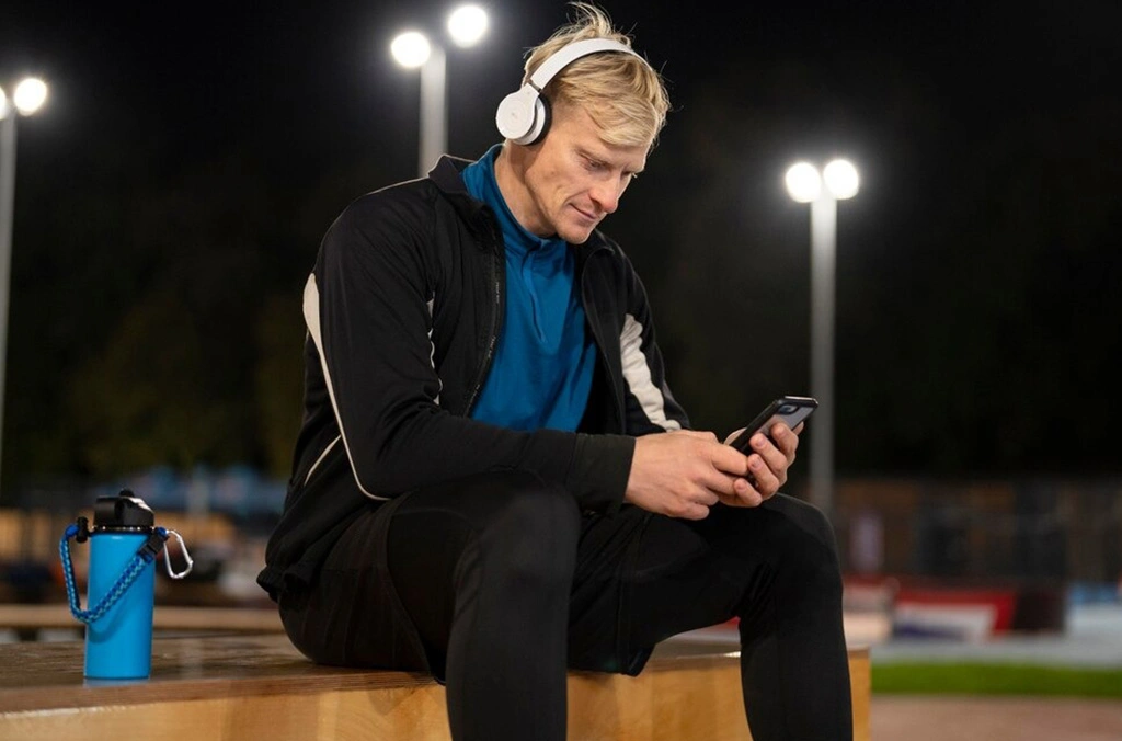 a man wearing headphones and looking at his phone